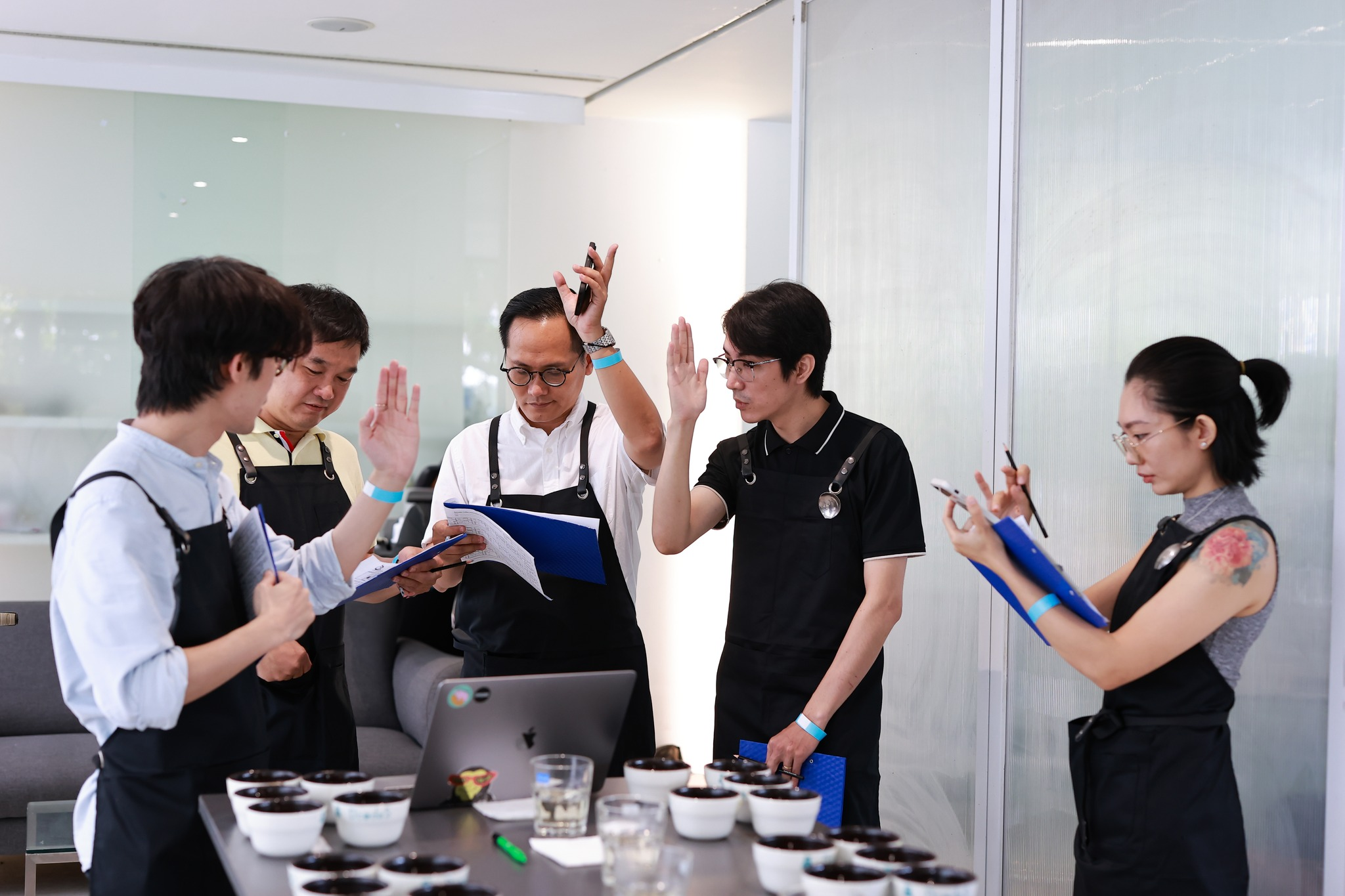 A group of people in aprons participating in a coffee tasting workshop.